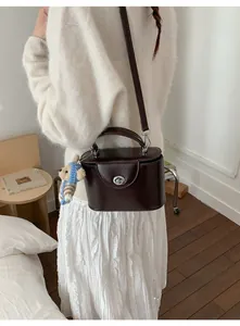 Détail du sac boîte marron rétro avec fermoir rotatif argenté et breloque ours