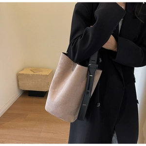 Detail view of large suede bucket bag with wide adjustable leather strap on model