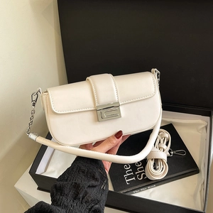 Minimalist creamy white leather crossbody bag with silver buckle on a gift box
