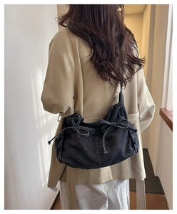 Detail of dark gray denim hobo bag featuring handmade bow ties on the shoulder strap