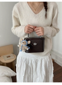 Detailed view of retro dark brown square handbag with metal lock and cute bear charm