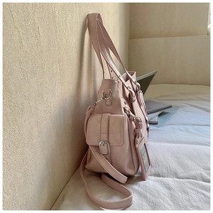 Detailed side view of pink tote bag with metal buckle pocket and adjustable strap