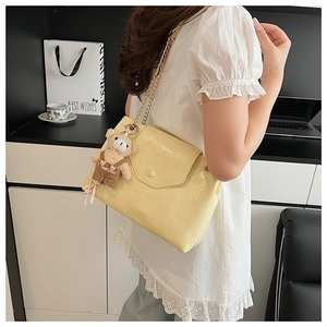 Détail du sac en cuir plissé jaune clair avec chaîne dorée et breloque ourson