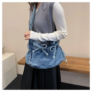 Detailed view of washed navy denim bucket bag with bow tie and drawstring closure