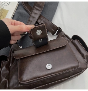 Detailed macro view of retro dark brown PU leather crossbody bag with silver magnetic buckle