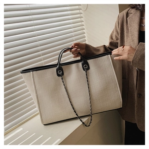 Detalle del bolso tote de lona con ribete de cuero negro y correa de cadena en modelo