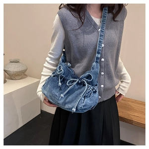 Detailed view of casual blue denim bucket bag with drawstring bows and shoulder strap