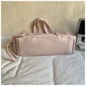 Detail of light pink leather tote bag featuring metal buckle and detachable shoulder strap