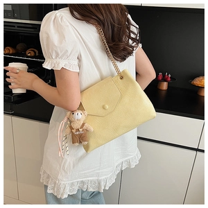 Détail du sac en cuir plissé jaune clair avec chaîne dorée et breloque ours en peluche