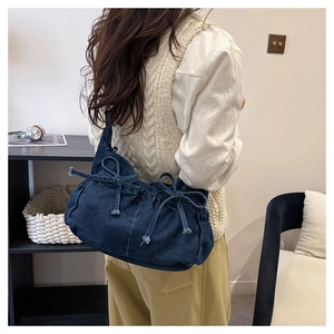 Detail of deep blue washed denim shoulder bag with soft pleated opening and bow accents