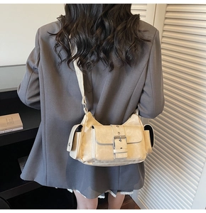Detail view of a beige retro messenger bag with large metal buckle on a model in a gray suit