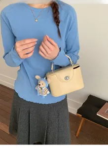 Détail du sac à main beige crème avec fermoir argenté et breloque ours au crochet
