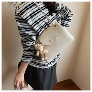 Détail du sac bandoulière plissé blanc crème avec chaîne dorée et breloque ourson
