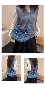 Close-up of blue denim bucket bag featuring dual bow drawstring and pleated details