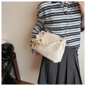 Détail du sac crème à texture froissée avec chaîne dorée et breloque ours mignon