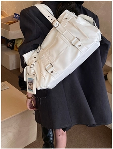 Detail of white large capacity PU shoulder bag with decorative straps and silver metal buckles