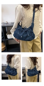 Detailed view of dark blue denim crossbody bag featuring bow accents and pleated texture