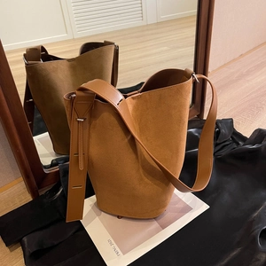 Classic caramel brown suede bucket bag with adjustable leather strap in mirror reflection