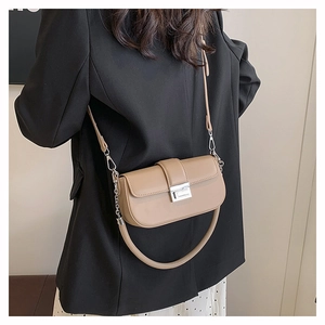 Detail of khaki leather baguette bag with silver buckle worn by a model in casual blazer