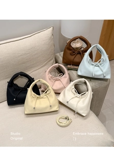 Detail showing various colors of dumpling bags in lychee grain leather with ribbon bows