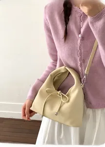Detail of soft beige leather bag with stylish bow drawstring and metallic strap buckle