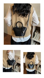 Détail du sac seau noir avec poignée ronde et pendentif en forme de cœur métallique