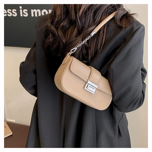 Detail view of khaki rectangular bag with silver chain strap on black blazer background