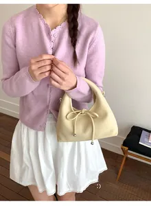 Detail of cream hobo bag with drawstring bow and textured leather finish