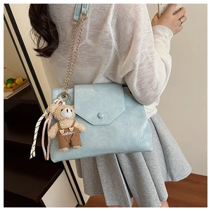 Sac bandoulière en cuir texturé bleu clair avec breloque ours et chaîne dorée