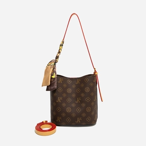 Détail du sac seau monogramme marron foncé avec bandoulière rouge et foulard en soie décoratif