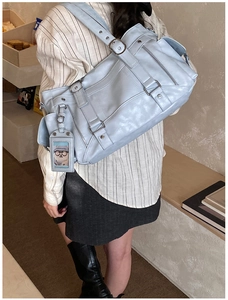 Detail of light blue vintage crossbody bag with silver zippers on a striped shirt model