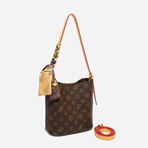 Détail d'un sac seau marron à monogramme avec foulard en soie et bandoulière bordée rouge