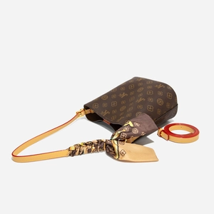 Détail d'un sac seau marron à monogramme avec foulard en soie et sangle en plus