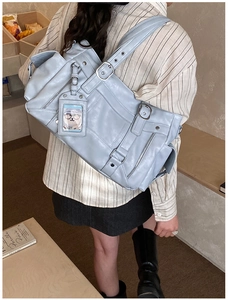 Detail of light blue multi-pocket crossbody bag with silver hardware and wide strap