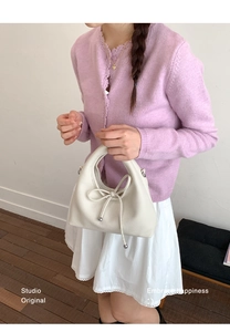 Detailed shot of white litchi pattern leather handbag with bow and metal ball charm