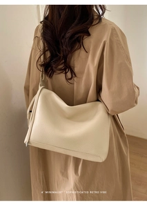 Detail of minimalist beige soft leather tote bag with rich texture worn by a model