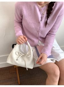 Close-up of white lychee pattern leather handbag with delicate bow detail on handle