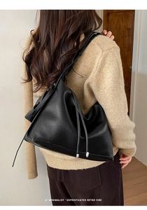 Detail of black lychee grain leather tote bag with silver metal hardware and hobo silhouette