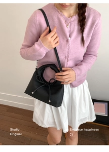 Detail of black crossbody bag featuring elegant bow tie decoration and metallic beads