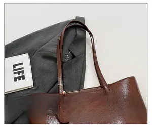Detailansicht der braunen Shopper-Tasche mit Fokus auf Schultergurtnaht und Metallschnalle