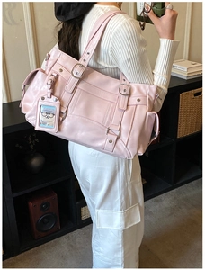 Detail of pink faux leather tote bag featuring functional buckles and side pockets