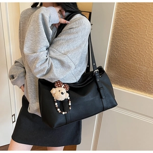 Détail du sac cabas en cuir grainé noir avec un charmant pendentif d'ours en peluche