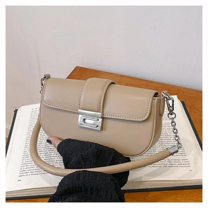 Close-up of khaki half-moon bag with chunky silver chain strap on a vintage book
