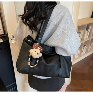 Détail d'un grand cabas en cuir grainé noir avec un porte-clé ours décoratif