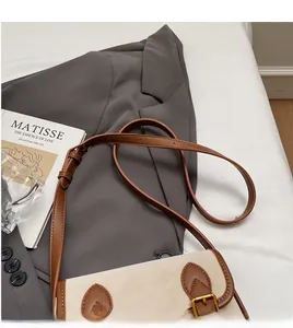 Détail de la bandoulière réglable en cuir et de la boucle en métal d'un sac baguette