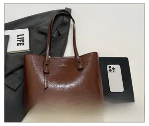 Detailansicht der dunkelbraunen Totebag aus Glanzleder mit feiner Textur und Logo-Detail