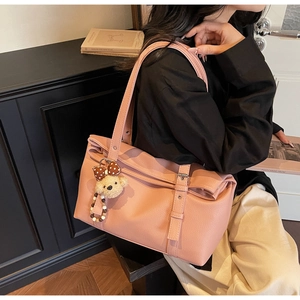 Détail d'un sac cabas en cuir rose à texture litchi avec breloque d'ours mignonne