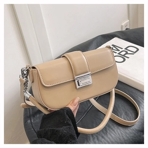 Detail of beige square shoulder bag with silver metal clasp and chain strap on magazine