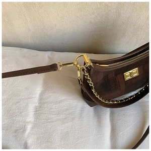Close-up of brown jacquard fabric and dark leather trim with gold metal chain