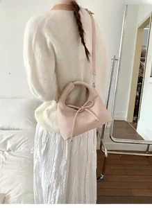 Pink lychee texture PU leather crossbody bag with bow tie detail shown on model